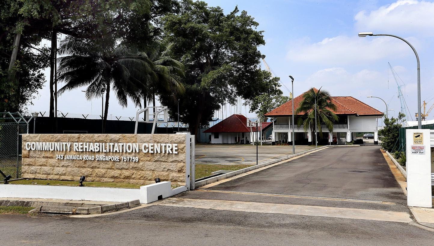 Community Rehabilitation Centre entrance with sign, trees, and a building with a red roof in the background.